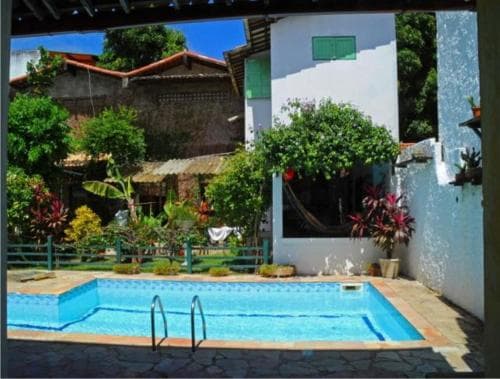 A serene tropical courtyard features a vibrant blue pool surrounded by lush greenery and colorful plants, ideal for a relaxing vacation retreat.