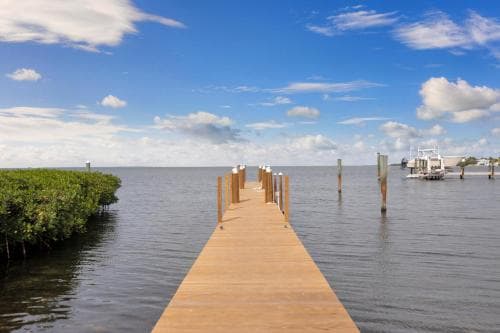A serene wooden pier extends into calm waters under a bright blue sky, ideal for tranquil waterfront relaxation or fishing trips.