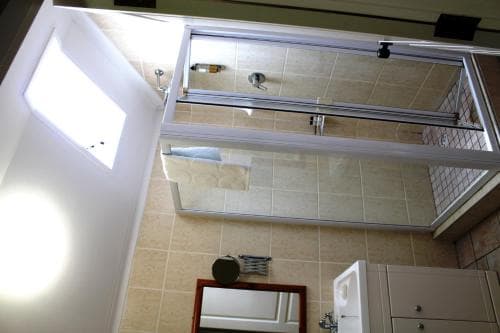 A cozy bathroom with tiled walls, a skylight, and a mirrored cabinet creates a bright and functional space ideal for travelers seeking comfort in compact accommodations.
