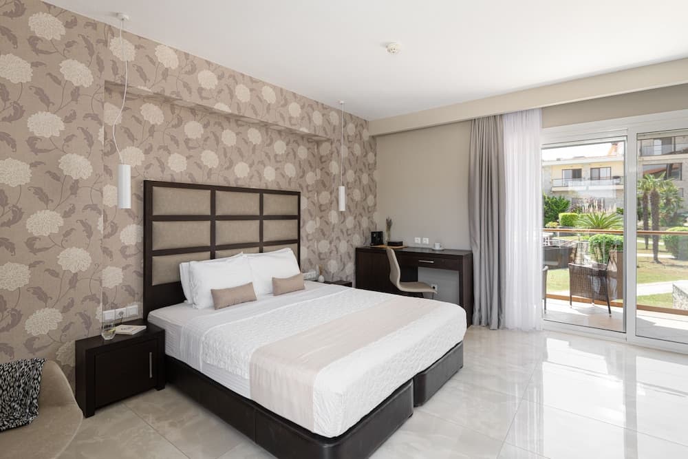 A cozy hotel bedroom with floral wallpaper, modern furnishings, and a balcony view of lush greenery offers a serene retreat for travelers seeking relaxation.