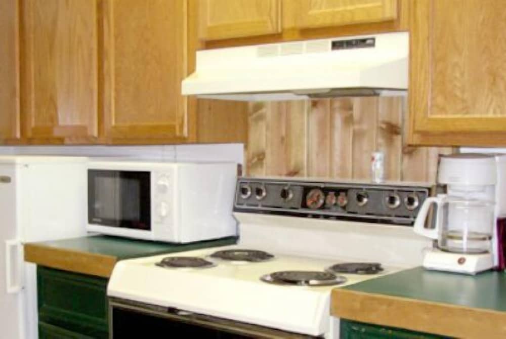 A cozy cabin kitchen featuring wooden cabinets, a white stove with black burners, a microwave, and a coffee maker, ideal for travelers seeking a homey cooking experience in a rustic setting.