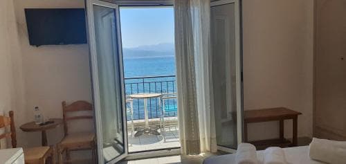 A cozy hotel room with an inviting balcony overlooking the serene ocean, featuring simple furnishings and a tranquil atmosphere perfect for a relaxing seaside getaway.