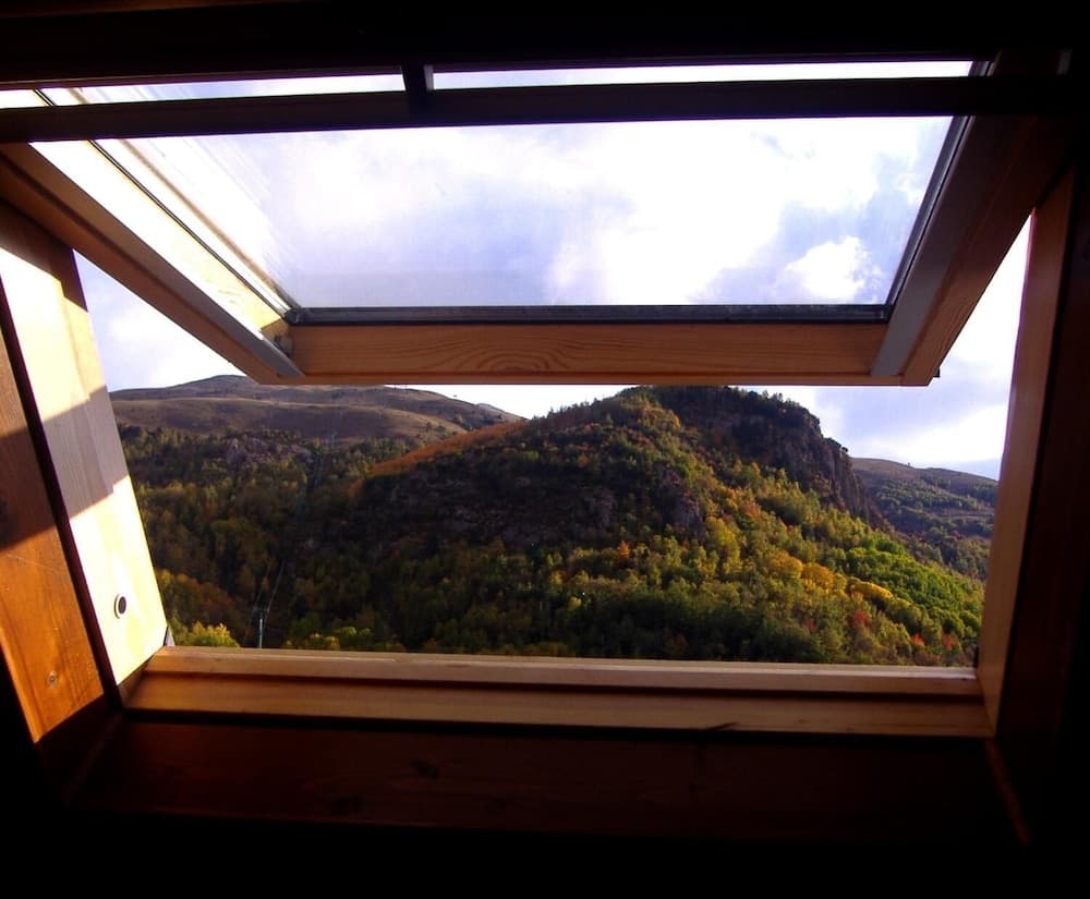 A serene view of autumn-colored mountains framed by a wooden window, ideal for travelers seeking tranquil retreats in nature.