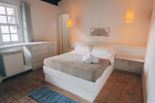 A cozy bedroom with terracotta flooring, soft lighting, and neatly arranged furnishings creates a serene atmosphere ideal for travelers seeking relaxation in a boutique hotel setting.