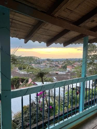 A serene balcony view captures a picturesque town nestled among lush green hills at sunset, ideal for travelers seeking tranquil retreats with scenic vistas.