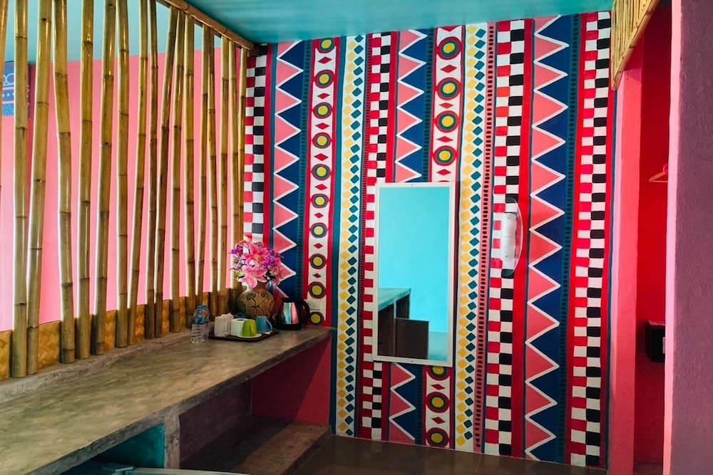 A vibrant, colorful bathroom with geometric-patterned walls, bamboo accents, and tropical decor creates a cheerful and exotic ambiance ideal for travelers seeking unique accommodations.