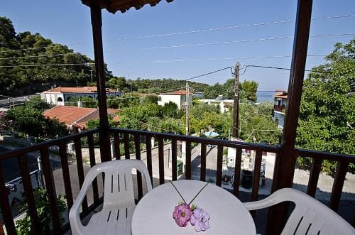 A serene balcony view overlooking a quaint seaside village with vibrant greenery, ideal for travelers seeking a peaceful coastal retreat.