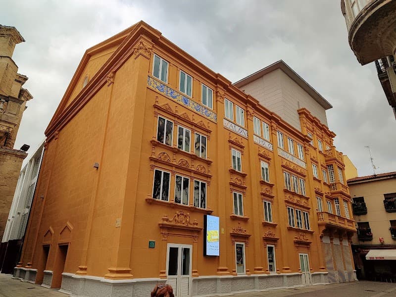 The vibrant orange facade of Teatro Apolo in Miranda de Ebro, Spain, stands out against the cloudy sky, inviting travelers to explore its historic charm and cultural events.
