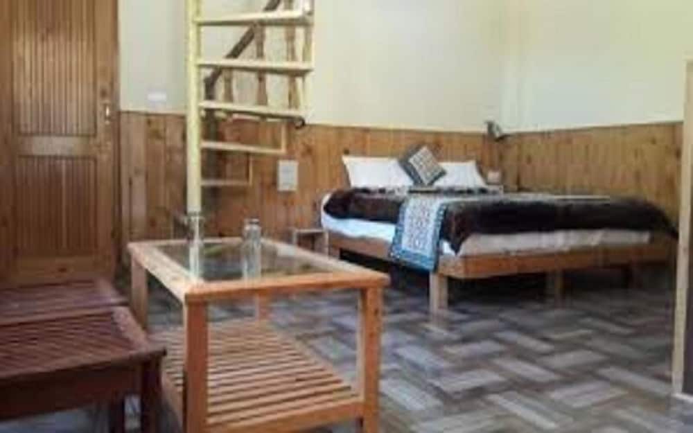 A cozy rustic bedroom with wooden furnishings, a ladder leading to an attic, and a patterned rug creates a warm and inviting atmosphere ideal for travelers seeking a charming retreat.