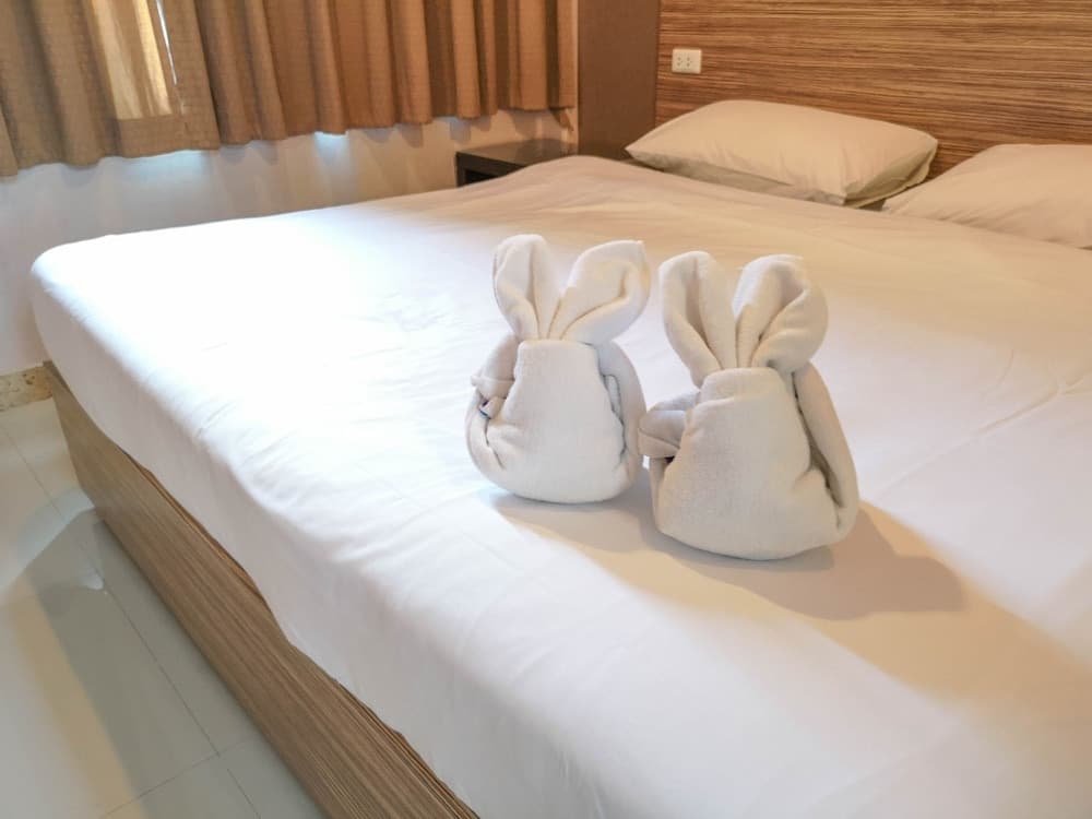 A cozy hotel room features a neatly made bed adorned with two charming towel bunnies, creating a welcoming and playful atmosphere ideal for family travelers seeking comfort and whimsy.