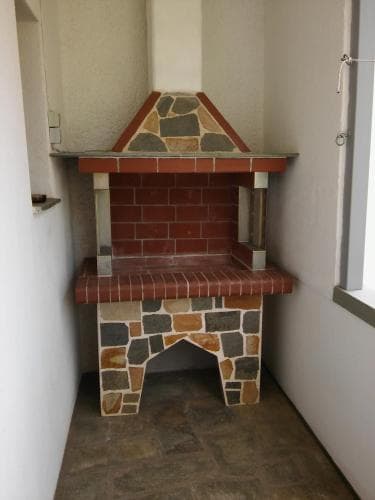 A cozy outdoor brick fireplace with a stone facade invites travelers to enjoy warm evenings in a rustic patio setting, perfect for camping or countryside retreats.
