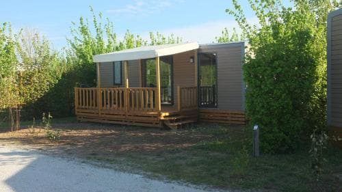 A cozy wooden cabin with a small porch nestled among lush greenery offers a serene retreat for nature lovers seeking a peaceful camping experience.