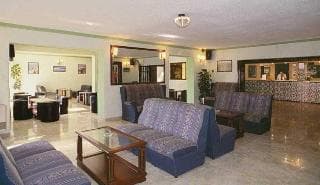 A cozy hotel lobby features plush blue sofas, a wooden coffee table, and polished marble floors, creating a welcoming atmosphere ideal for travelers seeking relaxation and comfort during their stay.