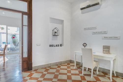A cozy indoor space with a checkered floor, white furniture, motivational wall art, and an open door leading to a patio, ideal for travelers seeking a relaxing and homey accommodation.
