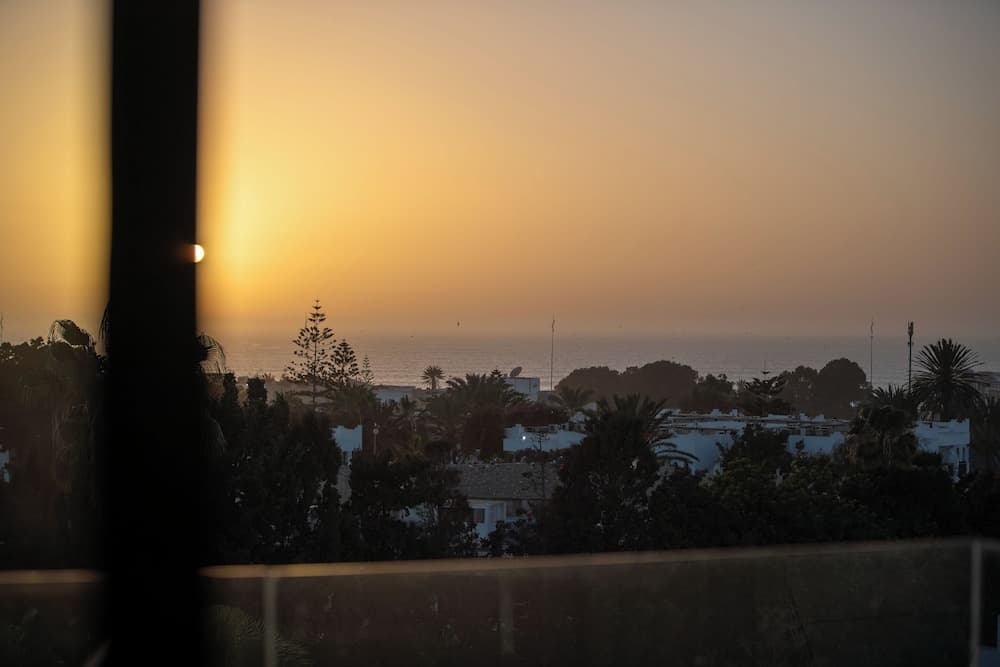 A serene sunset over a coastal town framed by lush greenery and white buildings, perfect for travelers seeking tranquil seaside relaxation.
