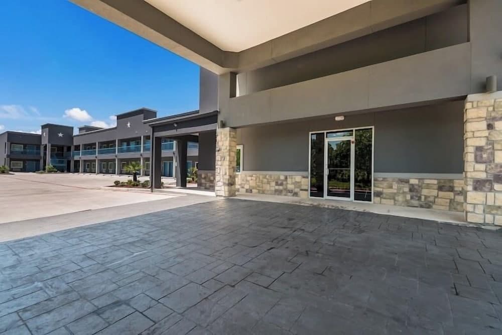 A modern hotel entrance with stone pillars and glass doors under a clear blue sky, ideal for travelers seeking a welcoming and stylish accommodation experience.