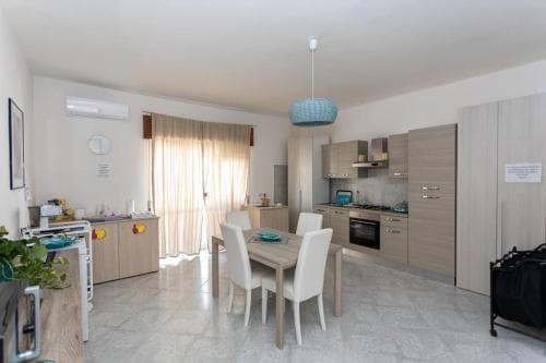 A cozy, modern kitchen-dining area with light wooden cabinets, a tiled floor, and a blue pendant light creates a welcoming atmosphere ideal for travelers seeking comfortable self-catering accommodations.
