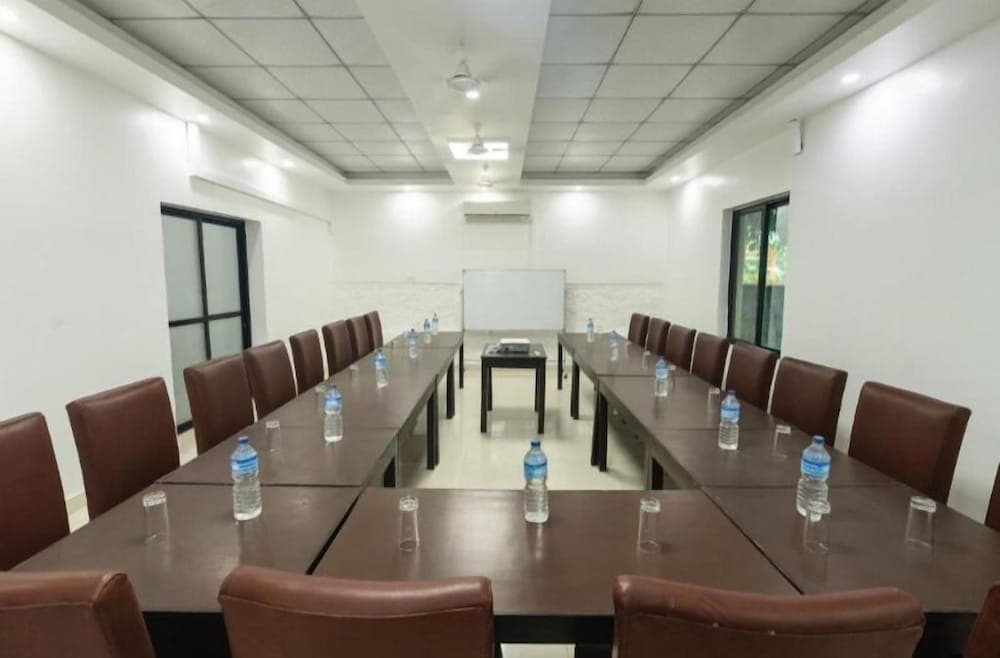 A modern conference room with long tables set for meetings, featuring water bottles and glasses, under bright fluorescent lighting, ideal for business travelers seeking professional venues.