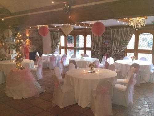A cozy banquet hall adorned with pink lanterns, draped tables, and twinkling lights creates an inviting atmosphere perfect for intimate gatherings or celebrations.