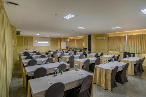 A well-lit conference room with neatly arranged tables and chairs, ideal for professional meetings or workshops, exudes a formal yet inviting atmosphere perfect for business travelers seeking a productive venue.