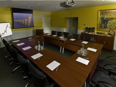 A vibrant yellow conference room set up for a professional meeting features modern tables, chairs, and presentation tools, ideal for business travelers seeking a productive workspace.