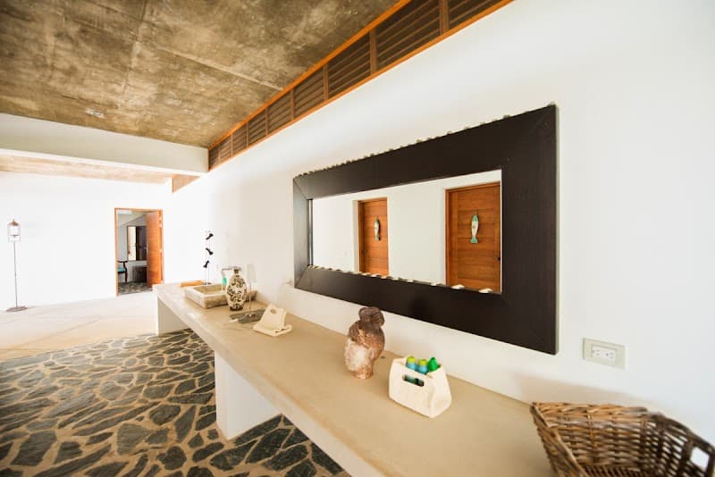 A serene entryway in a modern villa features a minimalist design with a sleek concrete countertop, a large mirror, and natural textures, ideal for travelers seeking a tranquil retreat in Las Terrenas, Dominican Republic.