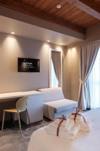 A cozy spa treatment room with soft lighting, wooden ceiling beams, neatly folded towels on the bed, and modern furnishings creates a serene atmosphere ideal for relaxation and wellness retreats.