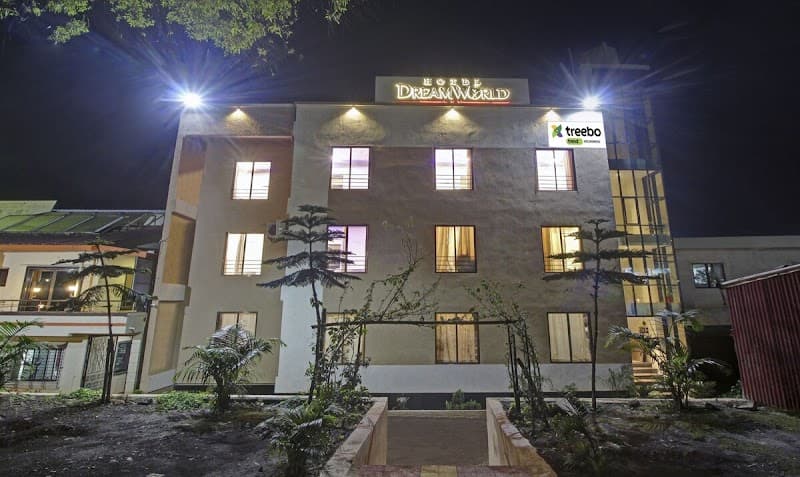 A cozy hotel illuminated at night along Mahabaleshwar Road in Maharashtra, featuring lush greenery and inviting windows, perfect for travelers seeking a serene getaway.