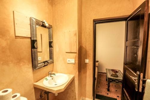 A cozy, rustic bathroom with warm-toned walls, a decorative mirror, and a small sink creates an inviting atmosphere, perfect for travelers seeking a charming and intimate accommodation experience.