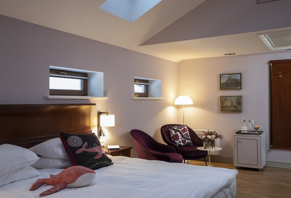 A cozy hotel room with a skylight, soft lighting, and quirky whale-themed decor creates an inviting atmosphere perfect for travelers seeking relaxation and comfort.