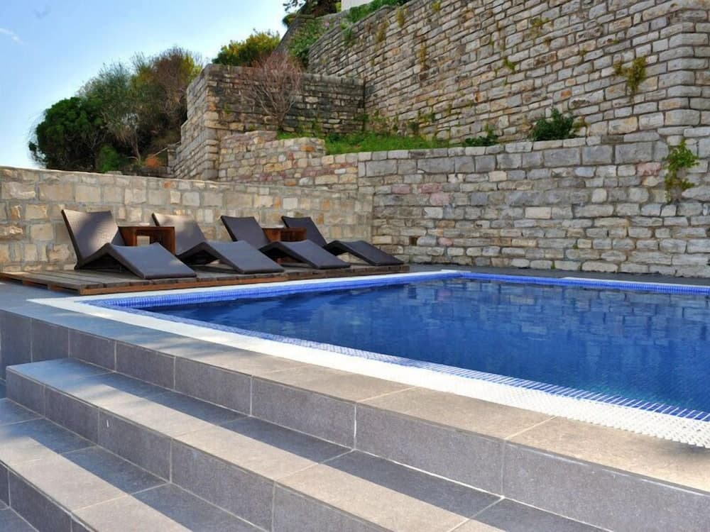 A serene private pool area with sun loungers and stone walls offers a tranquil retreat ideal for luxury vacation relaxation.