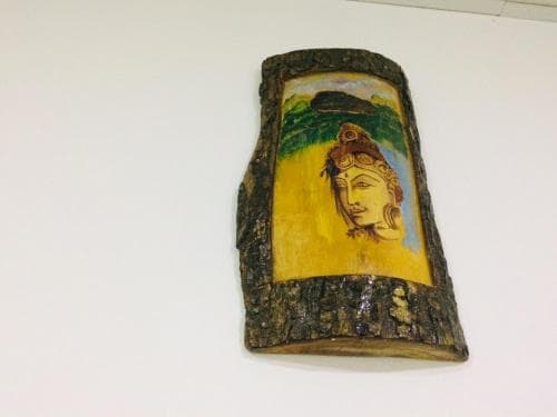 A serene wooden wall art piece featuring a painted Buddha face set against a vibrant yellow background, ideal for travelers seeking spiritual decor for their home or meditation space.