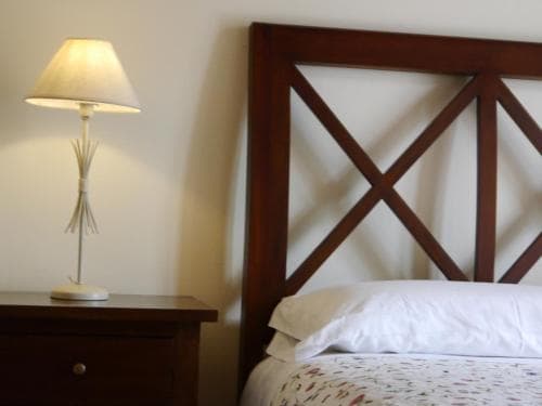 A cozy hotel room features a neatly made bed with a wooden headboard, a bedside table with a softly glowing lamp, creating a warm and inviting atmosphere ideal for travelers seeking comfort and relaxation.
