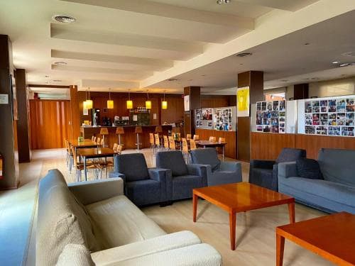 A cozy hotel lobby features modern seating arrangements, warm lighting, and a bar area, creating an inviting atmosphere ideal for travelers seeking relaxation or social interaction.