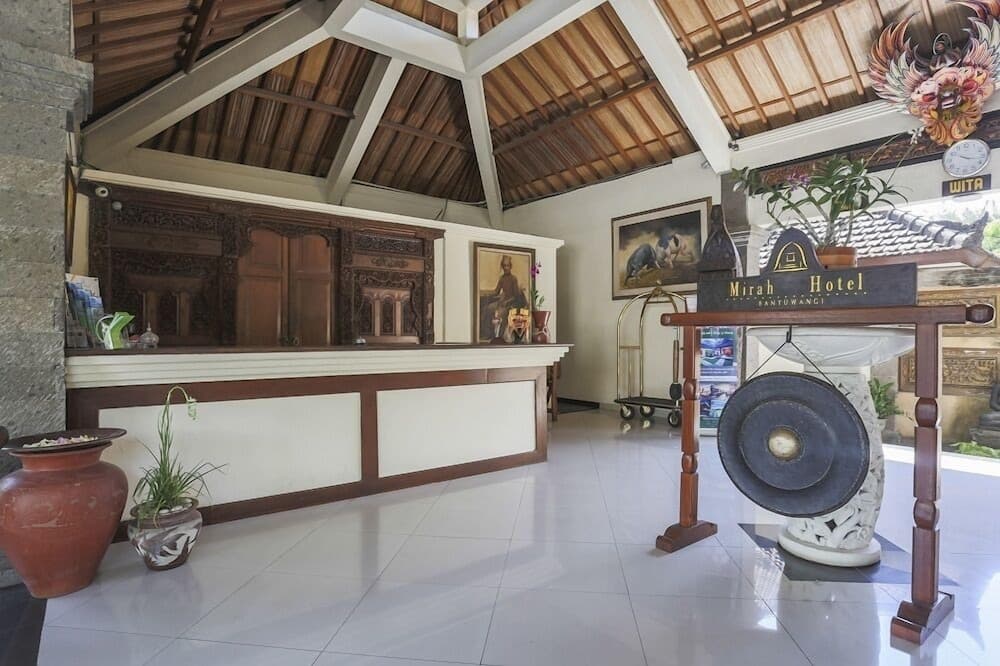 A serene hotel lobby with traditional wooden decor, a large gong, and cultural artwork creates an inviting atmosphere for travelers seeking a tranquil stay.