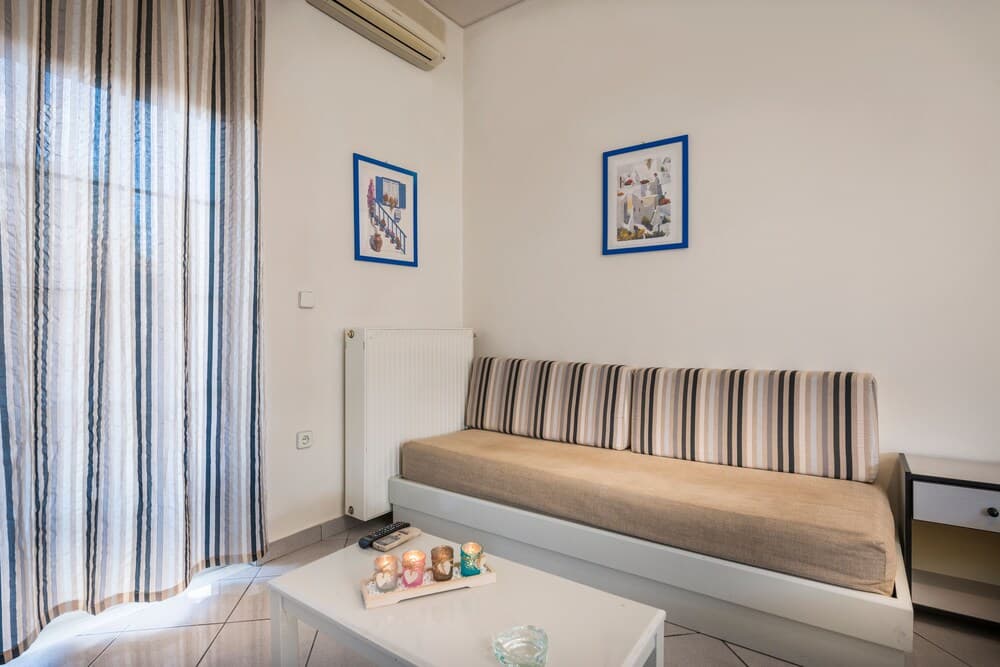 A cozy living room with striped curtains, a striped sofa, framed artwork, and a coffee table adorned with candles, ideal for travelers seeking a comfortable and inviting accommodation.