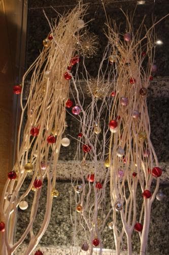 A festive indoor display features delicate branches adorned with colorful beads and ornaments, creating a whimsical and enchanting atmosphere ideal for holiday-themed travel experiences.