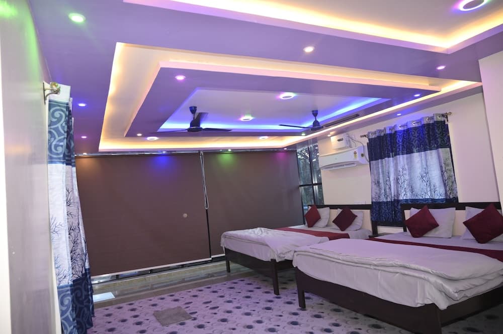 A cozy hotel room features two neatly made beds under a modern ceiling with colorful lighting, ideal for travelers seeking comfort and relaxation.