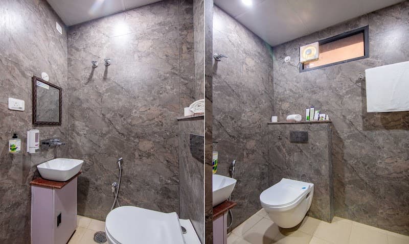 A modern bathroom with sleek marble walls, a vanity sink, and a toilet setup creates a clean and luxurious atmosphere, ideal for travelers seeking comfort at Treebo Ramayan Suites in Ayodhya, India.