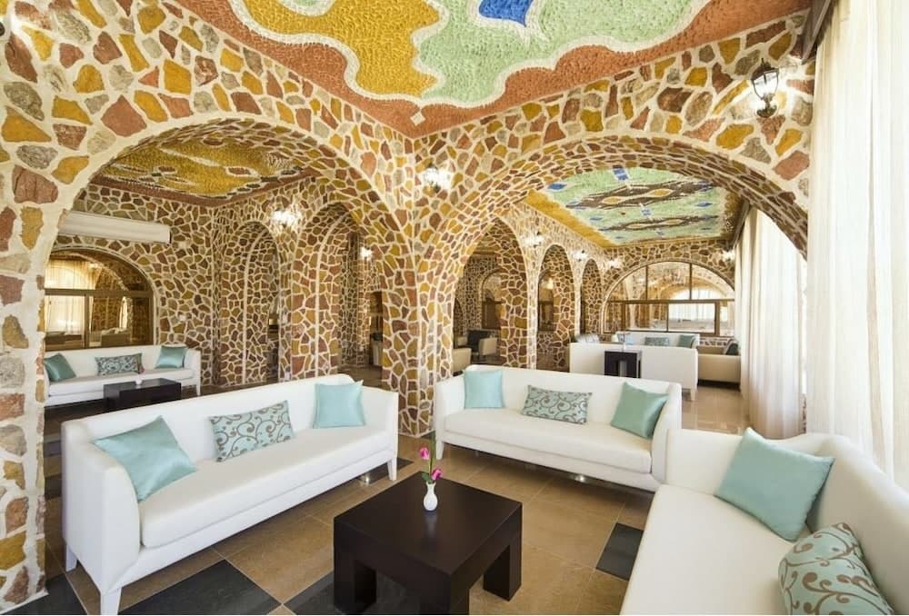 A vibrant, mosaic-adorned lounge with arched ceilings and plush white sofas creates an inviting atmosphere ideal for relaxation in a unique architectural retreat.