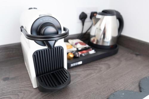 A cozy hotel room corner features a sleek coffee machine and kettle on a wooden tray, creating a welcoming atmosphere for travelers seeking a quick caffeine fix.