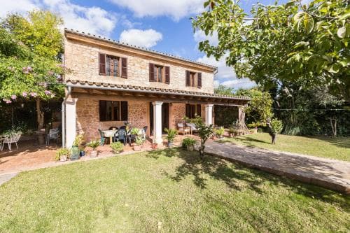 A charming stone villa with a cozy patio surrounded by lush greenery offers a serene retreat ideal for countryside relaxation and family vacations.