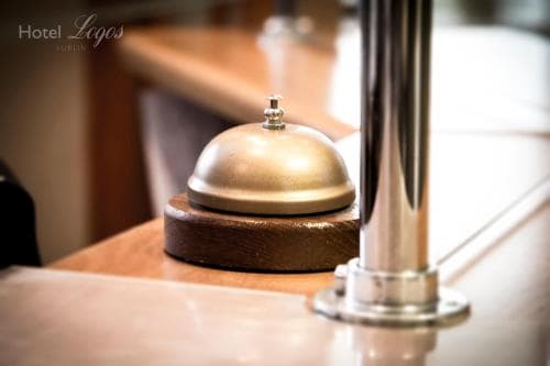 A close-up of a classic brass service bell on a wooden base at a hotel reception desk invites travelers to ring for assistance in a warm and inviting atmosphere.