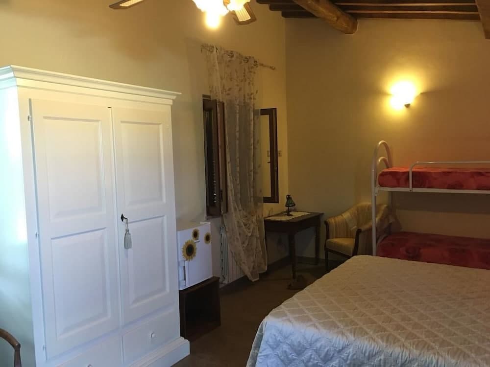 A cozy bedroom with warm yellow walls, wooden beams, a bunk bed, and a white wardrobe creates an inviting atmosphere ideal for family-friendly accommodations.