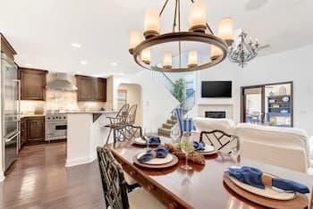 A cozy modern kitchen and dining area with warm lighting, wooden floors, and stylish furniture creates an inviting atmosphere perfect for family gatherings or home tours.