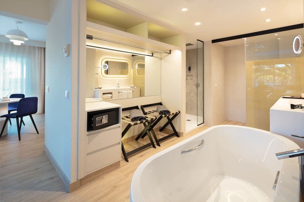 A luxurious hotel bathroom features a modern bathtub, glass-enclosed shower, and stylish vanity area, creating an inviting and serene atmosphere ideal for travelers seeking comfort and relaxation.