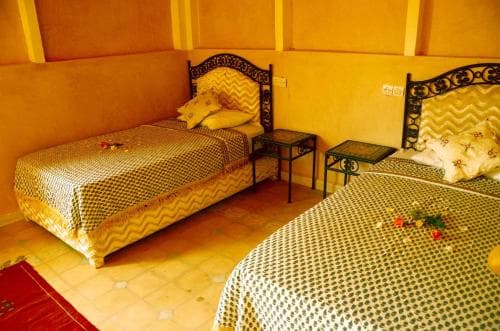 A cozy hotel room with two ornately framed beds adorned in patterned linens, set against warm-toned walls, exudes a welcoming atmosphere ideal for travelers seeking comfort and cultural charm.