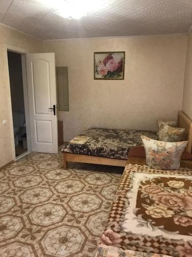 A cozy guesthouse room features patterned bedding, floral pillows, and a geometric-tiled floor, creating a warm and inviting atmosphere ideal for budget travelers seeking comfort.