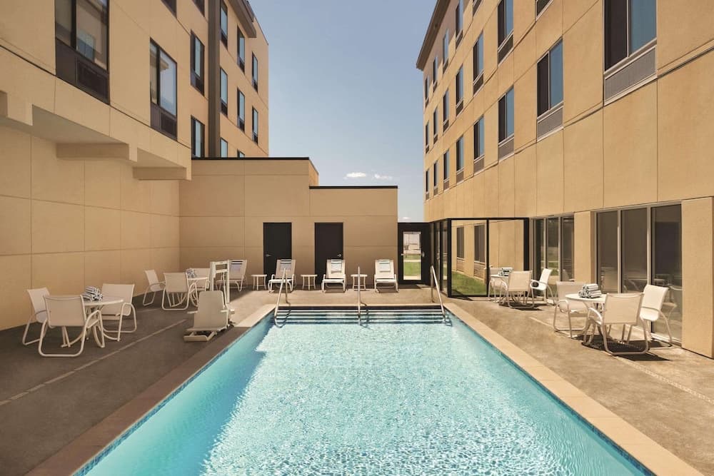 A serene hotel courtyard features a sparkling pool surrounded by lounge chairs and tables, offering a relaxing retreat for travelers seeking leisure and comfort.