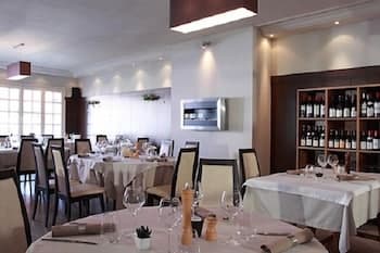 A cozy restaurant interior with neatly arranged tables, white tablecloths, wine racks, and soft lighting creates an inviting atmosphere perfect for a romantic dinner or a quiet evening out.